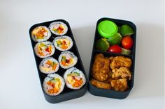 two black trays filled with different types of sushi next to each other on a white surface