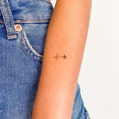 a woman's arm with a small arrow tattoo on the left side of her arm