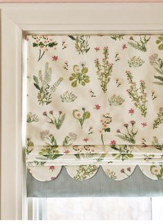 a window with a flowered valance hanging from it's side next to a window sill