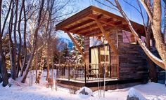 a small cabin in the woods with snow on the ground and trees around it at night