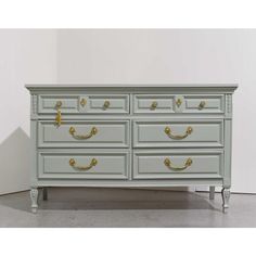 an antique dresser with gold handles and knobs on the drawers, painted in pale green