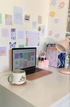 an open laptop computer sitting on top of a white desk next to a coffee mug