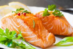 two salmon fillets on a white plate with garnish