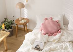 a bed with white sheets and pink pillows