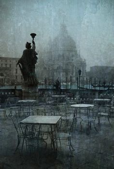 an outdoor cafe with tables and chairs in the rain