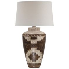 a brown and white vase with a light on it's side next to a lamp