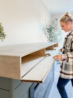 a woman standing in front of a desk with drawers on it and an open drawer