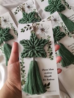 the green tassels are being held up by someone's hand and they have white flowers on them