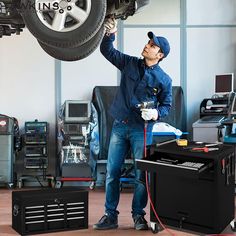 a man is working on a car in a garage with tools and equipment around him