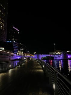 a bridge that has some lights on it and water in front of buildings at night