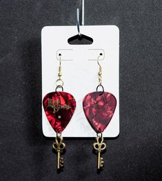 These Red Rock Steady guitar pick earrings are the perfect accessory to your night out! Made from upcycled material, and cast metal charm, these earrings are sure to be a great conversation starter.  All of the items in our shop are handmade with care. Unless otherwise specified, all of our beads are ceramic or glass and charms are cast metal. We consider small cosmetic flaws another facet of the beauty in our products, and often purchase or repurpose flawed or imperfect pieces for our work. However, none of these flaws should impact the durability of our jewelry. A note on purchasing earrings:  If you have a metal allergy please purchase with care as we do use a variety of wires and charms in our pieces. That being said, if you would like to request that we substitute nickel-free earring Edgy Red Earrings As Gift, Edgy Red Earrings For Gift, Edgy Red Earrings For Gifts, Guitar Earrings, Guitar Pick Jewelry, Guitar Pick Earrings, Rock Steady, Nickel Free Earrings, Allergy Friendly