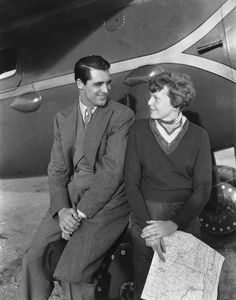 an old black and white photo of a man and woman in front of a plane