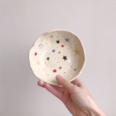 a hand holding a small bowl with stars on it