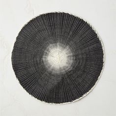 a black and white woven basket sitting on top of a table next to a wall