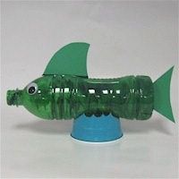 a green plastic toy fish sitting on top of a blue base with its mouth open