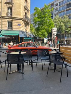 an orange car is parked in front of some tables and chairs