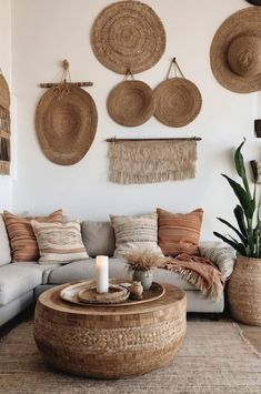 a living room filled with lots of pillows and wicker baskets hanging on the wall