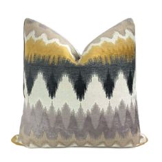 a yellow and grey pillow on a white background with an abstract design in the middle