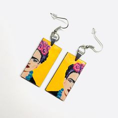 These Frida-inspired earrings are a true work of art, with each element carefully assembled by hand. Made with high quality acrylic paint and protected with a glossy finish, they are not only beautiful but also durable. With their light weight and one-of-a-kind design, they make the perfect gift for someone special. A truly unique accessory for a truly unique person. Size: 3/4 Inch x 1.5 Inch each (without including earrings hook wires).______________________________________ • GET IT FAST!Get it fast! Ready to ship on 1 to 3 business days* • ORDER NOW!Limited Quantities / Limited Edition. • FREE GIFT BOX INCLUDED!Fridamaniacs delivers every jewelry or gift order in a gift box. Thank you for shopping with us!____________________________ * Colors/Designs might slightly vary from actual. Our Yellow Hand Painted Artsy Earrings, Hand Painted Yellow Artsy Earrings, Artistic Hand Painted Yellow Earrings, Artistic Hand Painted Earrings, Yellow Earrings With Artistic Design For Gift, Artsy Yellow Earrings With Artistic Design, Artistic Hand Painted Earrings For Gifts, Hand Painted Resin Earrings In Artsy Style, Hand Painted Rectangular Earrings Gift