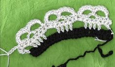 three crocheted headbands on top of a green cloth covered in white and black yarn