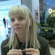 a woman with long blonde hair holding up a pair of glasses