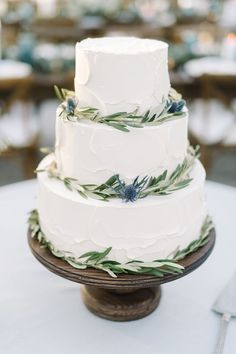 a white wedding cake with greenery on top