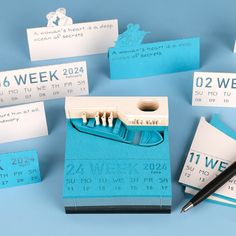 a bunch of blue and white business cards next to a pen