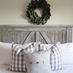 a white bed topped with two pillows and a wreath on top of the headboard