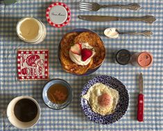 a table topped with plates and cups filled with desserts next to utensils