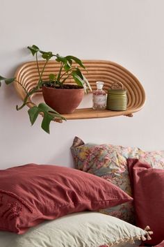 a bed topped with pillows next to a wooden shelf filled with plants and potted plants