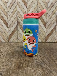 a children's sippy cup with an image of a shark and fish on it