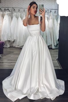 a woman taking a selfie while wearing a wedding dress in front of a mirror