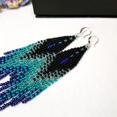 Seed Bead Earrings 4 inch long.Flowing beads earrings.The predominant colors are black, gray , Dark purple and Emerald green color . Sterling silver ear wire.Different shades of colors seamlessly blend into each other.These are luxurious earrings for every day and also for an evening out. Materials; Japanese beads. Czech beads. sterling silver 925 ear wire. Luxurious Earrings, Seed Bead Jewelry Patterns, Popular Trends, Japanese Beads, Long Tassel Earrings, Luxury Earrings, Turquoise And Purple, Beads Earrings, Long Dangle Earrings