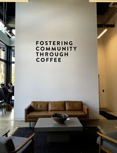 a coffee shop with couches and tables in front of a wall that says fostering community through coffee