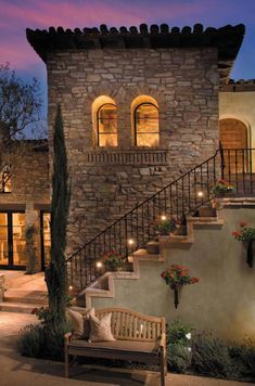 a stone house with stairs leading up to the front door and steps down to the second floor