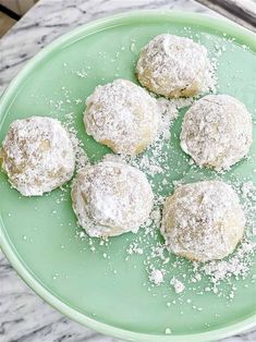 four powdered sugar cookies on a green plate