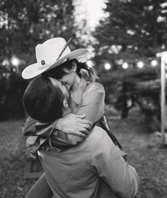 a woman in a cowboy hat hugging a man with his face close to her chest