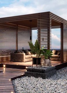 an outdoor living area with wood slats and plants on the ground, along with rocks