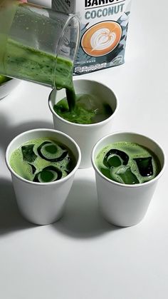 three cups filled with green liquid being poured into them