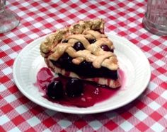 a piece of pie sitting on top of a white plate covered in blueberry sauce