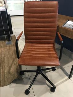 a brown leather office chair sitting on top of a white tile floor