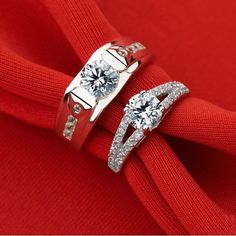 two wedding rings on top of each other with diamonds in the middle and red fabric