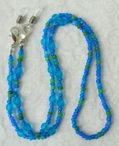 You'll always know where your eyeglasses are when you use this light blue beaded eyeglass chain! 26.5" in length, made with glass beads, beading cord, metal lobster clasps, and adjustable rubber holders. Lobster clasps make it easy to change the rubber holders, and an extra pair of holders included with every purchase. This light blue beaded eyeglass chain will arrive in a gift box, ready to give as a present or to keep and store. Back to Beaded Eyeglass Chains Blue Beaded Jewelry For Everyday Use, Everyday Blue Beaded Jewelry, Blue Beaded Glass Glasses Chains, Blue Round Beads Jewelry For Everyday, Adjustable Blue Glasses Chains With Colorful Beads, Handmade Adjustable Blue Glasses Chains, Blue Beaded Chain Glasses Chains With Round Beads, Blue Adjustable Necklace For Everyday Use, Blue Beaded Glasses Chains