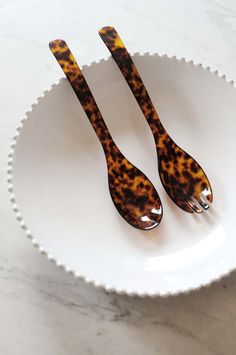 two tortoise shell utensils in a white bowl