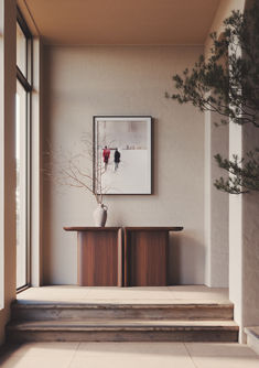 a vase with flowers sitting on top of a wooden table next to a staircase leading up to a window