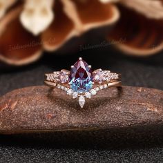 a blue and white diamond ring sitting on top of a wooden surface with flowers in the background