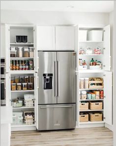 a stainless steel refrigerator in a kitchen with white cabinets and shelves filled with food items