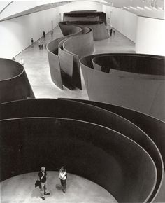 black and white photograph of two people standing in the middle of a large circular structure