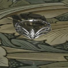 a close up of a ring on a surface with leaves and flowers in the background