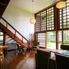 a living room filled with lots of furniture next to a wooden stair case and windows